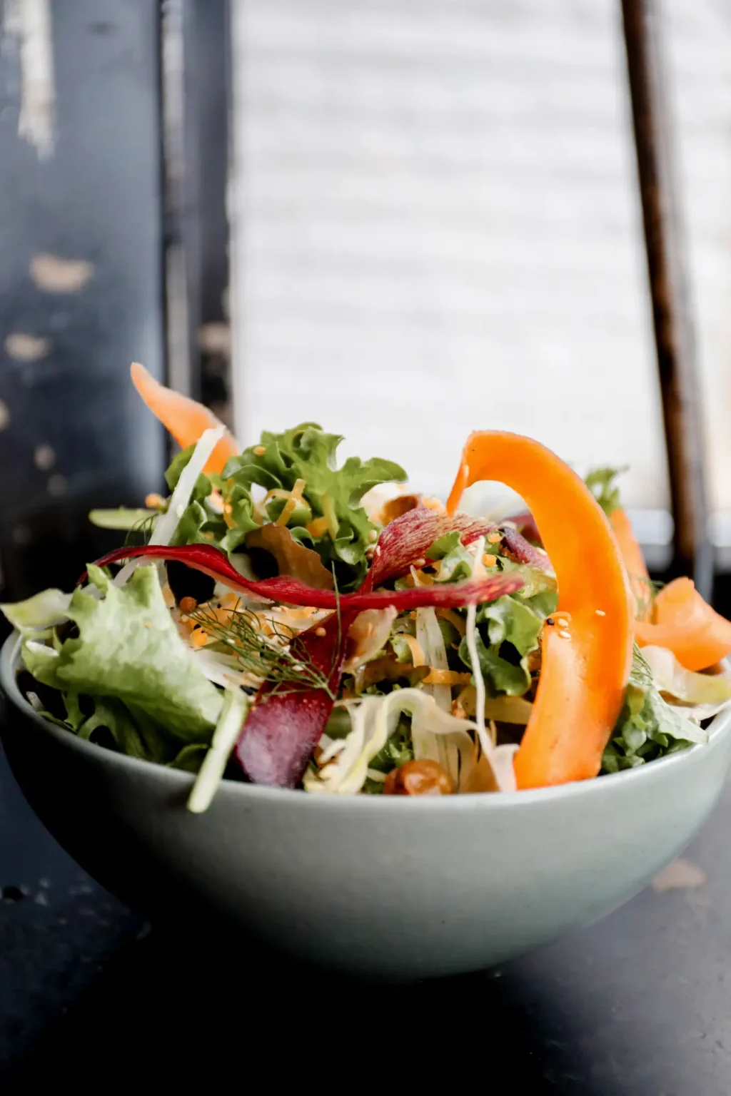 A bowl of garden greens with shaved carrot and beet