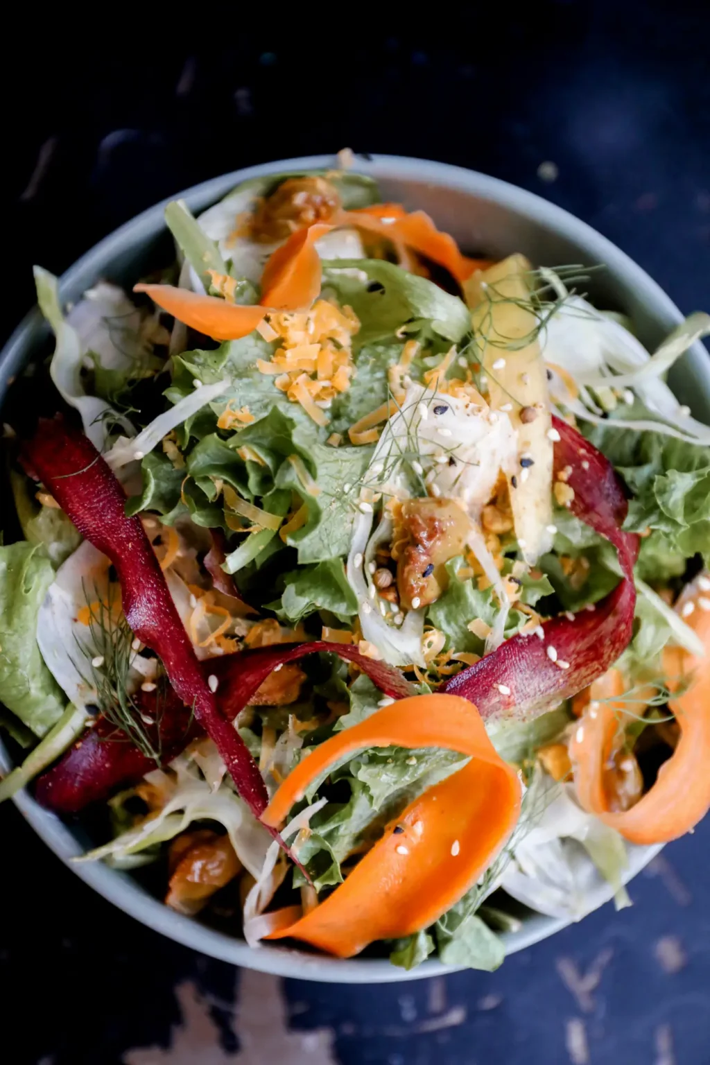 A garden salad of greens, shaved carrot ribbons and beets, seen from above